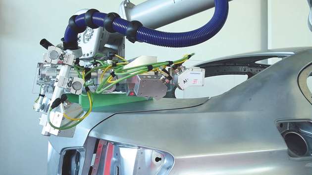 Der Roboter führt die vormontierte Heckklappe zur Karosse, wo die exakte Einbauposition mit einem Laserscanner ermittelt wird.
