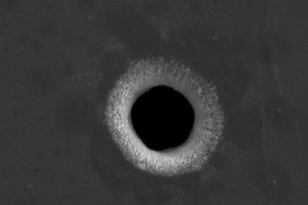 Mikrobohrung in einer Edelstahlfolie mit einem Austrittsdurchmesser von unter 10 µm.
