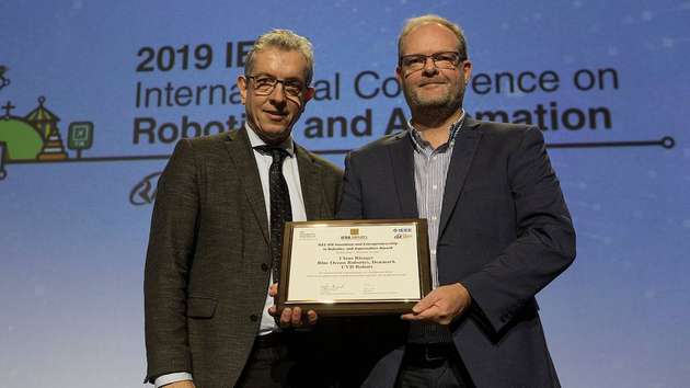 Wolfram Burgard, Präsident von IEEE RAS und Claus Risager, CEO Blue Ocean Robotics, mit dem IERA-Award.