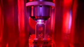 Ein fluoreszierender organischer molekularer Kristall befindet sich im Kryostat (Kühlgerät für sehr tiefe Temperaturen) eines optischen Mikroskops. Bei Quantencomputern auf Basis von Festkörperspins sind die Rechen- und Speichereinheiten in die Kristallstruktur von Festkörpern eingebettet.