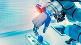 Industrieroboter positioniert ein Bauteil auf einer Vorrichtung für automatisierte Montageprozesse.