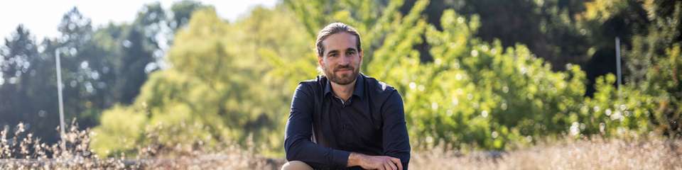 Der Physiker Dr. Lukas Wagner zwischen Solarmodulen auf dem Dach des Physikgebäudes der Universität Marburg. Mit Prof. Dr. Jan Christoph Goldschmidt und weiteren Forschenden hat er in einer aktuellen Studie untersucht, welche Nachhaltigkeitsziele Photovoltaik für eine globale Hochskalierung erfüllen muss.