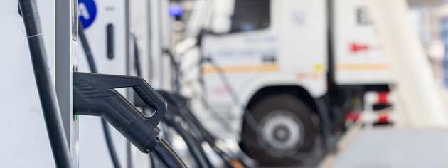 Bei der Depotladung mehrerer E-Lkw steuert ein Energiemanagementsystem die DC-Ladevorgänge fahrzeugscharf und bindet den Netzanschluss, den Batteriespeicher und die Photovoltaikanlage in einen Ladeplan ein.