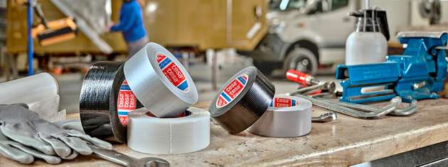 Tesa-Klebebänder in verschiedenen Ausführungen auf einer Werkbank – typische Einsatzmittel für Abdecken, Befestigen und Reparieren in industriellen und handwerklichen Anwendungen.