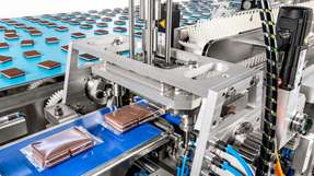 Die Abbildung zeigt eine horizontale Schlauchbeutelmaschine, in der Produkte automatisiert in Folien verpackt werden – ein Verfahren, das je nach Packstoff per Hitze-, Klebe- oder Ultraschallsiegelung realisiert wird.