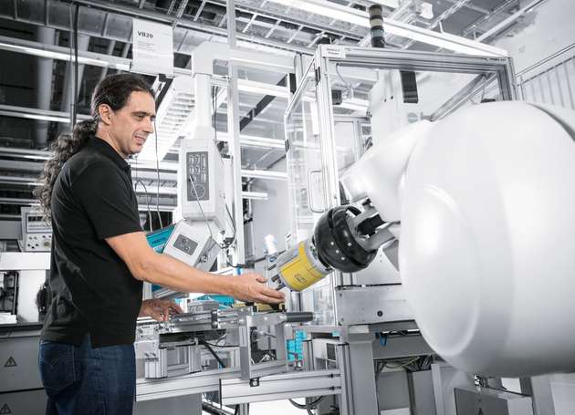  Festo-Mitarbeiter interagieren direkt und ohne Schutzkäfig mit dem Montageroboter.