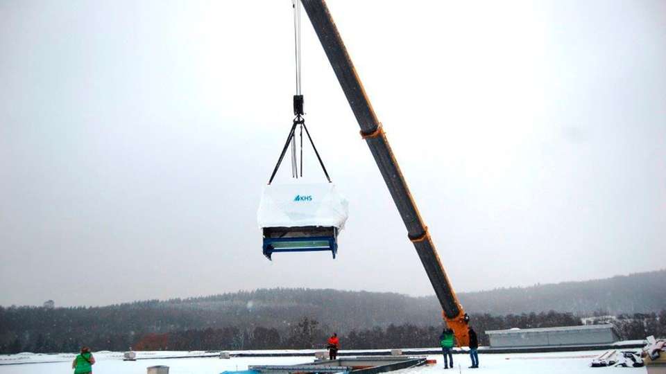 Spektakuläre Aktion: Ein 500-Tonnen-Kran hieft die 14 m lange Flaschenreinigungsanlage durch eine eigens dafür geschaffene Dachöffnung in den Füllbetrieb.