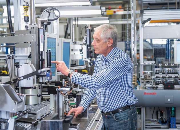 Ein Mitarbeiter bedient an der vernetzten Multiproduktlinie von Bosch ein Touch-Panel zur Auswahl eines Montageprogramms.