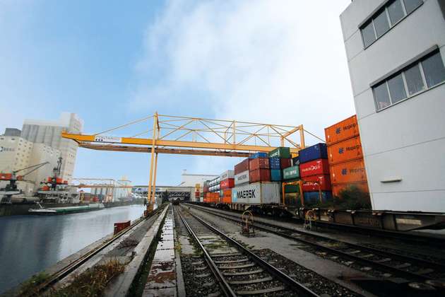 In einem trimodalen Hafen werden Container zwischen Schiff, Bahn und LKW hin und her verladen.