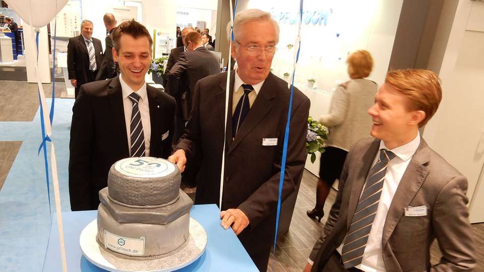 Pflitsch-Geschäftsführer Harald Pflitsch (m.) schneidet gemeinsam mit der nächsten Unternehmer-Generation Roland Lenzing (l.) und Mathias Stendtke (r.) die Jubiläumstorte im Uni-Dicht-Design an.