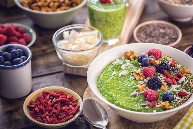 Green Breakfast Smoothie in Bowl with Superfoods on Top