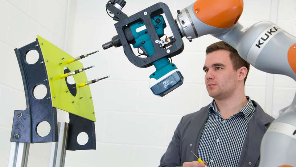  Der Kuka iiwa Roboter hilft einem Werker beim Einführen von Nieten am Modell eines Bauteils aus der Luftfahrtindustrie.