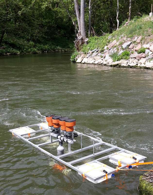 Feldversuch mit Degreen-Generatoren in einem Fließgewässer. Die Anregung der Silikonmembranen erfolgt über den Unterdruck in den wasserdurchströmten Venturi-Rohren unter dem Floß.