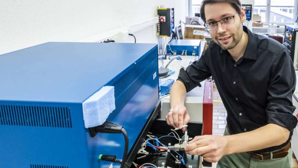 Batterieforschung: Ruben Simon Kühnel forscht an wässrigen Elektrolyten für künftige Lithium-Ionen-Zellen. Hier platziert er Versuchszellen in ein Messgerät, um sie wiederholt zu laden und zu entladen.