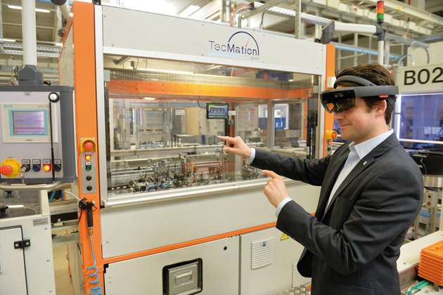 Nähert sich Dr. Patrick-Benjamin Bök der Spritzgussmaschine, legt sich ein 3D-Modell in leuchtenden Umrissen über die reale Anlage.