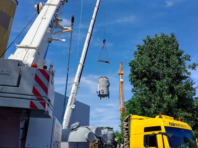 Der erste der drei Elektrodenkessel hängt am Haken und wird durch das noch offene Dach des Anlagengebäudes bugsiert.