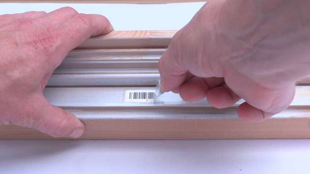 Ein transparentes Laminatetikett, das das Basisetikett beim Überlackieren geschützt hat, wird wieder abgezogen.