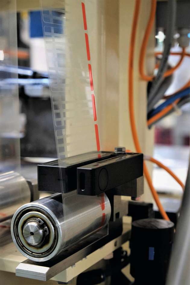 Der Ultraschall-Etikettensensor UGUTI 6/70, Trägerfolie mit transparenten Klebeetiketten (rot: Abziehgriff).