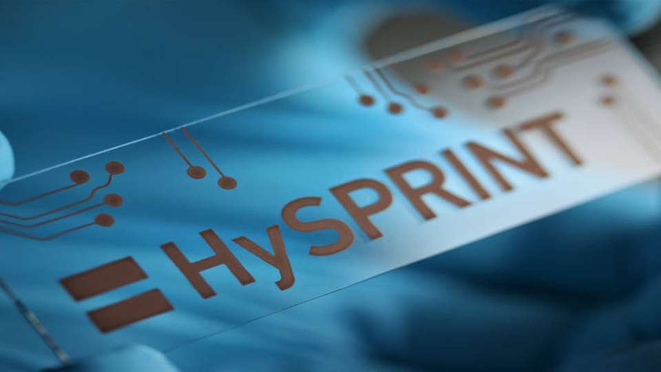 Das aus einer Kupferlösung aufgedruckte HySPRINT-Logo (Helmholtz Innovation Lab) symbolisiert, wie sich dünnste Materialschichten kostengünstig herstellen lassen.