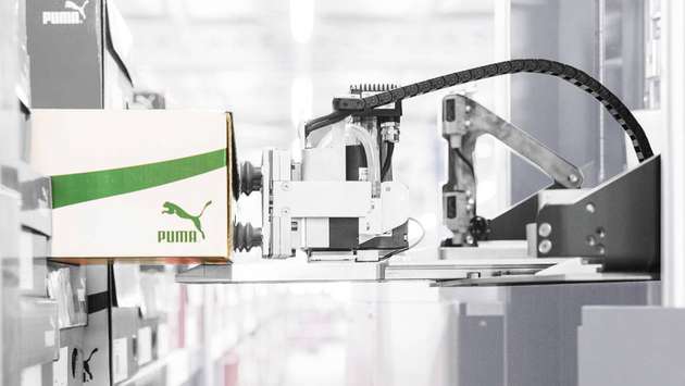 Per Unterdruck werden die Waren aus dem Regal genommen. Eine Metallzunge schließt vor dem Ansaugen die Lücke zwischen Regalboden und dem Logistikroboter. Sowohl das Ausfahren der Zunge als auch das Bewegen des Greifarms übernehmen bürstenlose DC-Servomotoren von Faulhaber.