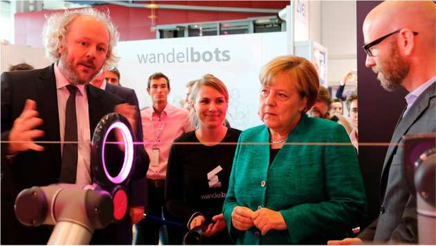Wandelbots kooperiert unter anderem mit der Deutschen Telekom. Professor Frank Fitzek, Deutsche Telekom Chair of Communication Networks an der Technischen Universität Dresden, zeigt Bundeskanzlerin Angela Merkel eine Anwendung der Wandelbox.