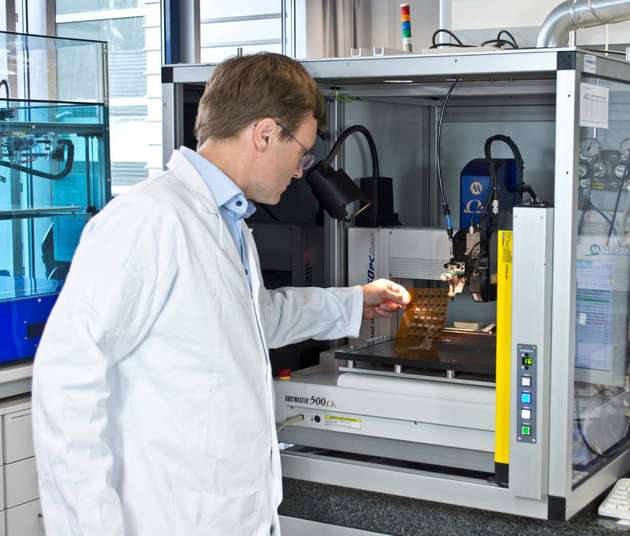 Dr. Roman Tkachov begutachtet an einem Dispensdrucker im Fraunhofer IWS eine Folie, die er mit zwei verschiedenen leitenden Polymeren bedruckt hat.