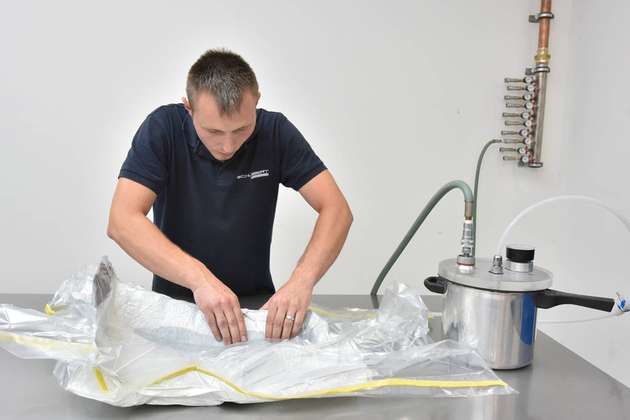 Der Schlauch wird mit dem Umweg über einen Topf, der angesaugtes Material auffängt, an die Vakuumpumpe von Atlas Copco angeschlossen. In weniger als einer Minute ist die Luft aus dem Bag evakuiert.