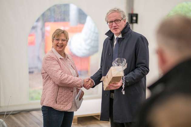Mendens stellvertretende Bürgermeisterin Brigitta Erdem überreicht Bürkert-CEO Heribert Rohrbeck beim Spatenstich ein Geschenk.
