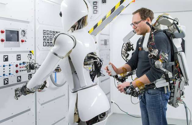 Ein Operator steuert den humanoiden Roboter AILA mihilfe eines Oberkörper-Exoskeletts in einem Nachbau der ISS.