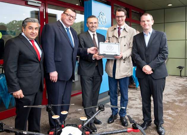 Verkehrsminister Hendrik Wüst (vierter von links) erhält die ersten von der Transportdrohne gelieferten Rohstoffproben als Geschenk. Mit dabei (von links nach rechts): Premal Desai, Vorstandsmitglied für Finanzen hei Thyssenkrupp Steel Europe; Andreas Goss, Vorsitzender des Vorstands von Thyssenkrupp Steel Europe; Thomas Jarzombek, Koordinator der Bundesregierung für die Deutsche Luft- und Raumfahrt und Dr. Thomas Lostak, Projektleiter.