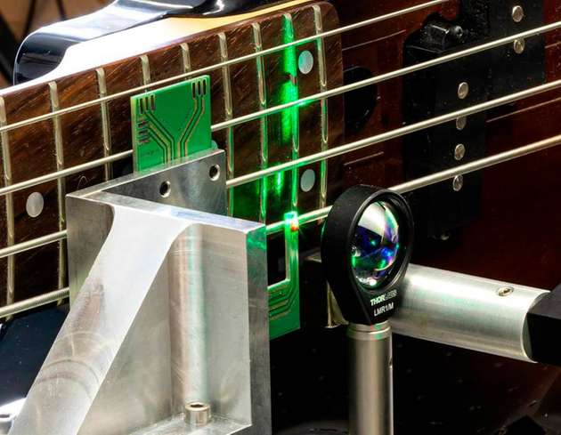 Im Experiment werden die Saiten einer Gitarre mit einem roten Diamanten zum Klingen gebracht.