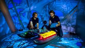 Zwei Freiberger Informatiker an dem neu entwickelten Schwimmroboter „Elisabeth“ in der CAVE.