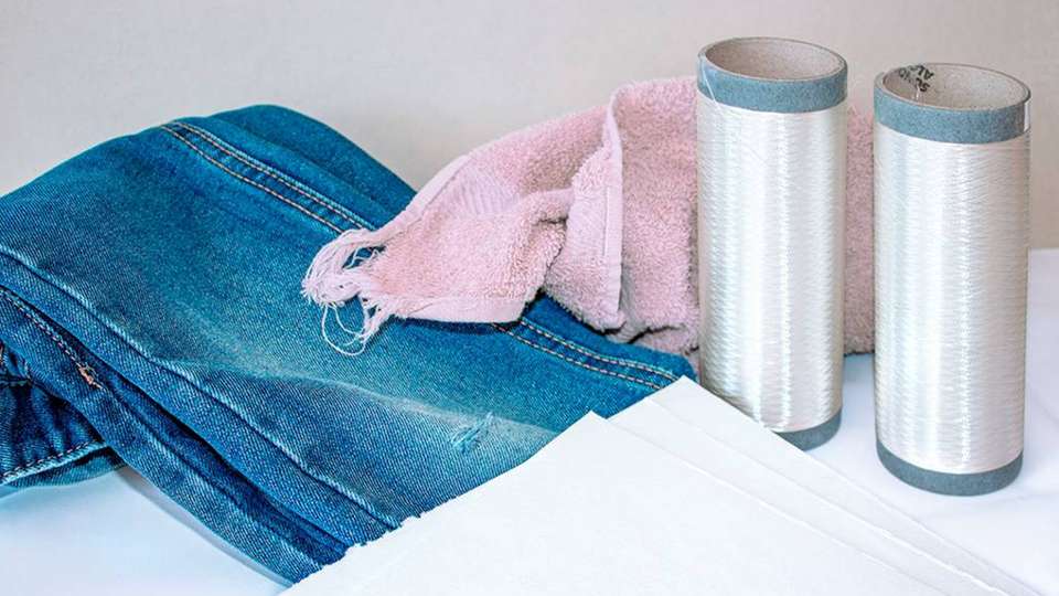 Das aufgespulte Viskose-Filamentgarn wurde aus recycelter Baumwolle gefertigt, die in Form von Zellstoffplatten vorliegt. Aus Baumwollkleidung wie Jeans können so erstmals hochwertige neue Kleidungsstücke werden.