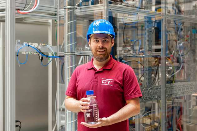 Jakob Burger, Professor für Chemische und Thermische Verfahrenstechnik, vor der neuen Demonstrationsanlage in München: Die Flasche enthält in dieser Anlage hergestellten OME.