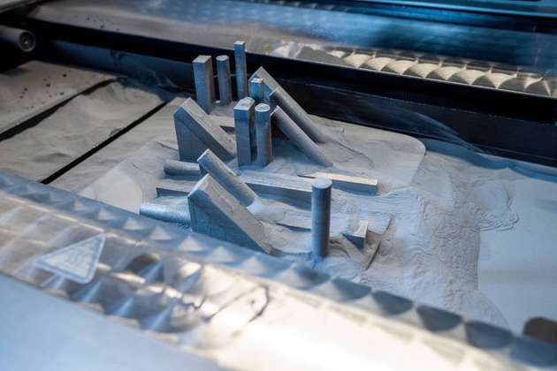Im Pulverbettverfahren entsteht das Bauteil Schicht für Schicht. Überschüssiges Metallpulver lässt sich meist weiterverarbeiten.