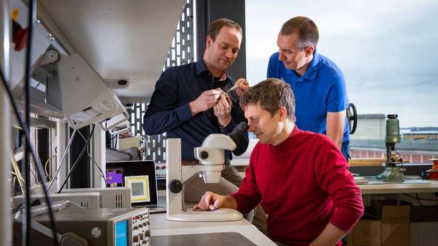 Blick ins Labor: Forscher der TU Chemnitz um Marko Rößler (am Mikroskop) entwickelten einen hocheffizienten Mikrochip zur exakten Positionsbestimmung in Gebäuden.