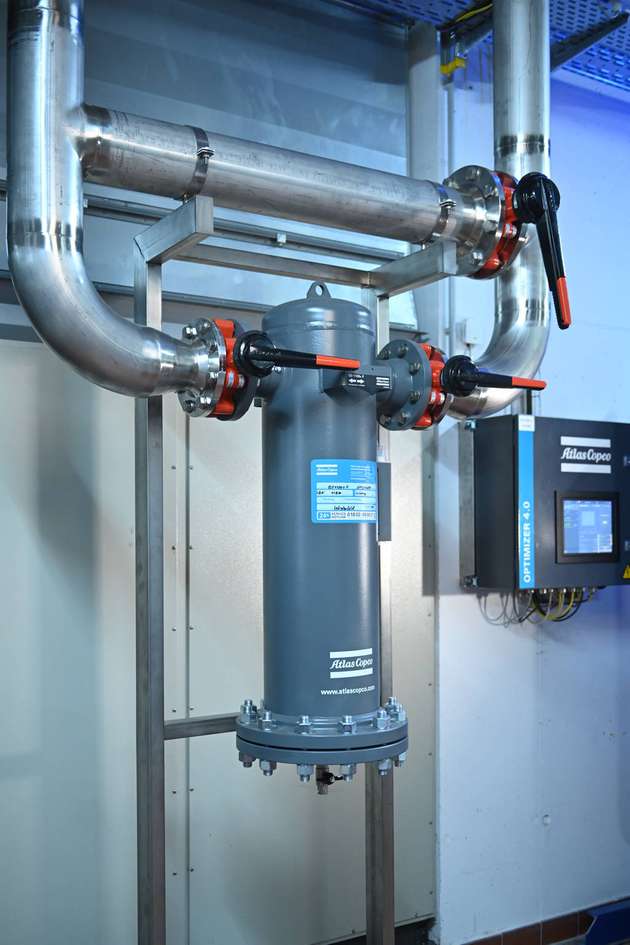 Jede Druckluftstation verfügt über einen Aktivkohlefilter (Bildmitte), um etwaige Öl-Aerosole und Dämpfe, die sich in der Raumluft befinden könnten, sicher abzuscheiden. Rechts an der Wand befindet sich der Optimizer 4.0, die neue übergeordnete Steuerung von Atlas Copco. 