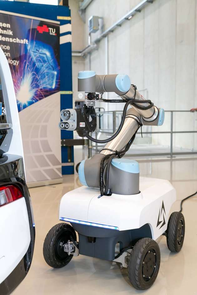 Der automatisierte Roboterarm führt das Ladekabel millimetergenau zur Ladebuchse des Fahrzeugs und ist auf eine autonom navigierende mobile Plattform montiert.

