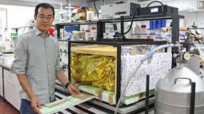 Dr. Qimeng Song bei seiner Arbeit an dem neu entwickelten Messaufbau. Hinter der gold glänzenden Folie verbirgt sich eine schwarze Kuppel, die auf - 195 °C heruntergekühlt ist und so den kalten Nachthimmel imitiert.