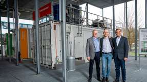 Leigh Hackett (links) und Saurabh Kapoor (rechts) von Metafuels und Marco Ranocchiari vom PSI (Mitte) auf der ESI-Plattform – hier entsteht eine neue Pilotanlage aus zwei Container-Modulen, um synthetisches Kerosin aus erneuerbaren Ressourcen herzustellen.