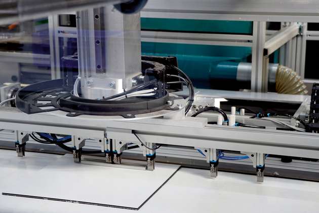 Mit einer Genauigkeit von einem zehntel Millimeter werden die Leisten auf dem Alu-Dibond aufgeklebt. 