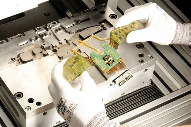 Hotmelt Moulding am Beispiel eines Feuerwehrhelms. Mittig zu erkennen: Steckverbinder, die mittels Dam & Fill ausgespart wurden.