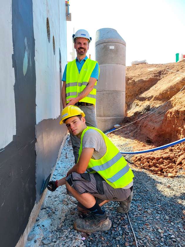 Simon Bickert (Vordergrund) macht die Mauern winterfest. Projektleiter Stefan Reith freut sich, dass die Partnerunternehmen perfekt Hand in Hand arbeiten.