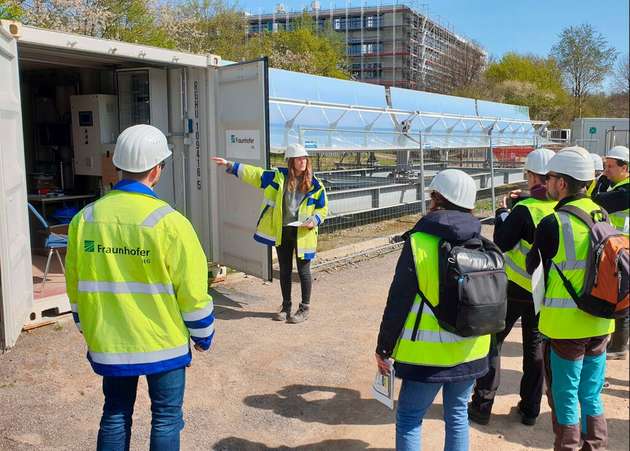 Mit Besuchern besichtigt Arianna Passamonti die Gesamtanlage samt Solarthermieanlage, die ihre im Sommer gesammelte Wärme in 64 m Tiefe in Grubenwasser speichert.