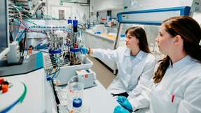 Stefanie Duvigneau (rechts) und Anna-Sophie Neumann (links) arbeiten gemeinsam im Labor an der Biopolymerproduktionsanlage.