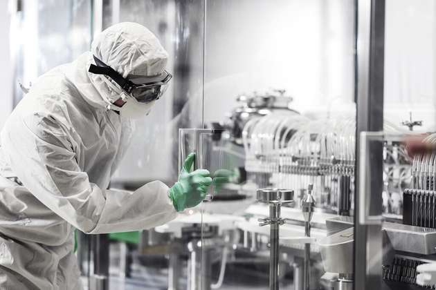 Ein Mitarbeiter in einem Reinraum inspiziert eine Produktionsanlage zur Herstellung steriler pharmazeutischer Produkte – ein zentrales Thema des überarbeiteten EU GMP Annex 1, der auf modernste Barriere-Technologien und Automatisierung setzt, um Kontaminationen zu minimieren.