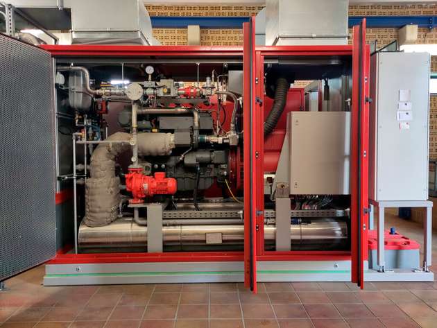 Ein BHKW besteht im Wesentlichen aus einem Motor (Mitte rechts), der in der Regel mit Gas betrieben wird und gleichzeitig Strom erzeugt sowie Wärme abgibt. Diese Abwärme wird über Wärmetauscher (links unten) zur Beheizung von Räumen oder Brauchwasser genutzt. Die Regelungseinheit (ganz rechts) steuert den Betrieb.