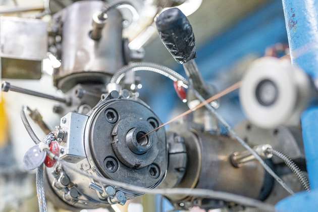 Ein Extrudor bringt eine Kunststoffschicht auf das Kupfer auf. 