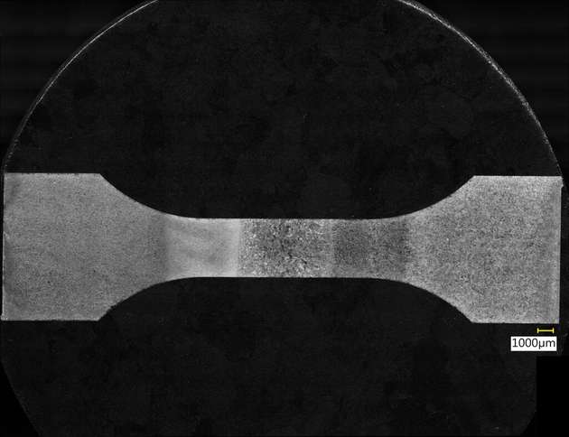 Eine Probe unterm Digitalmikroskop. Rechts ist der gegossene Stahl zu sehen, links der gedruckte, in der Mitte die Schweißnaht. Es ist deutlich zu erkennen, dass die Wärmeeinfluss unterschiedliche Auswirkungen auf die verschiedenen Materialien hat.