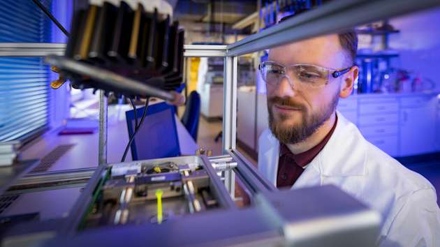 Raphael Hertel, Wissenschaftlicher Mitarbeiter der Professur Polymerchemie, führt eine Zug-Dehnungs-Messung an einer Probe im Labor durch.